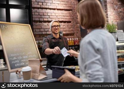small business, payment, people and service concept - happy barman and woman with wallet paying money at cafe. happy barman and woman paying money at cafe
