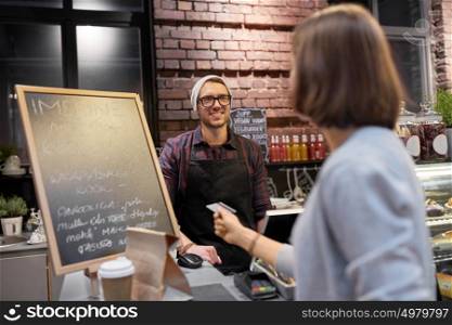 small business, payment, people and service concept - happy barman and woman paying with credit card at cafe. barman and woman paying with credit card at cafe