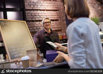 small business, payment, people and service concept - happy barman and woman with wallet paying money at cafe. happy barman and woman paying money at cafe