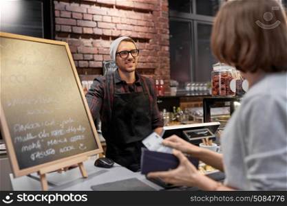 small business, payment, people and service concept - happy barman and woman with wallet paying money at cafe. happy barman and woman paying money at cafe. happy barman and woman paying money at cafe