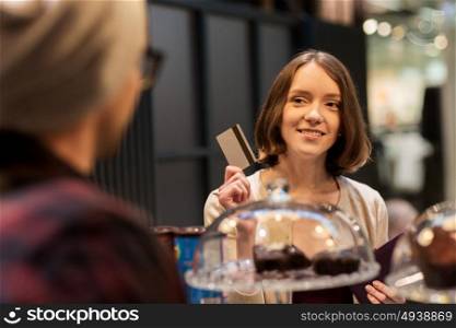 small business, payment, people and service concept - happy woman with credit card buying cakes at vegan cafe or coffee shop. happy woman with credit card buying cakes at cafe
