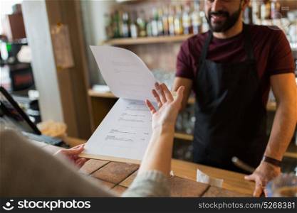small business, people and service concept - bartender and customer menu at bar or coffee shop. bartender and customer menu at bar
