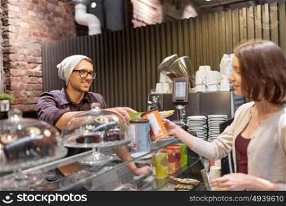 small business, people and service concept - happy female customer buying chai latte instant drink and man or waiter at vegan cafe. happy woman buying chai latte drink at vegan cafe