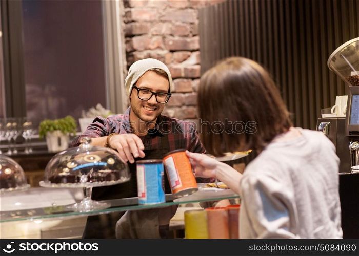 small business, people and service concept - happy female customer buying chai latte instant drink and man or waiter at vegan cafe. happy woman buying chai latte drink at vegan cafe. happy woman buying chai latte drink at vegan cafe