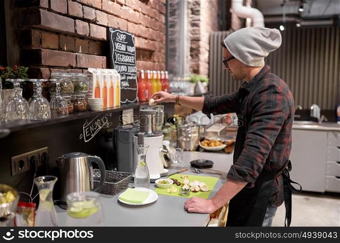 small business, people and service concept - happy man or barman with blender cooking smoothie at vegan cafe. man or barman cooking smoothie at vegan cafe