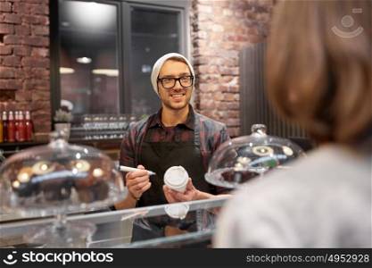 small business, people and service concept - happy man or barman with coffee cup and marker serving female customer at vegan cafe. man or barman with coffee cup and customer at cafe