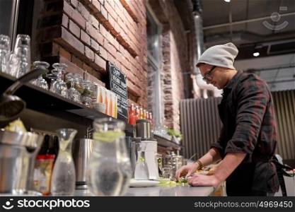 small business, people and service concept - happy man or barman with blender cooking smoothie at vegan cafe. man or barman cooking smoothie at vegan cafe