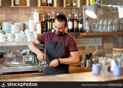 small business, people and service concept - happy man or waiter in apron with holder and tamper preparing espresso at coffee shop. barista with holder and tamper making at coffee