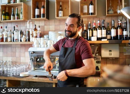 small business, people and service concept - happy man or waiter in apron with holder and tamper preparing espresso at coffee shop. barista with holder and tamper making at coffee