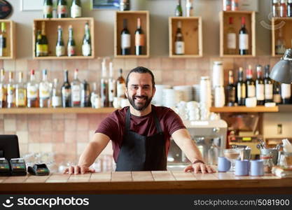 small business, people and service concept - happy man or waiter in apron at bar or coffee shop. happy man, barman or waiter at bar