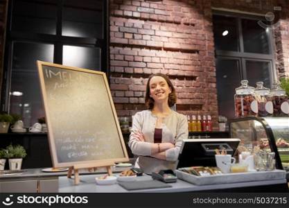 small business, people and service concept - happy woman or barmaid at counter with cashbox in cafe or coffee shop. happy woman or barmaid at cafe counter