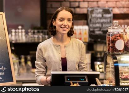 small business, people and service concept - happy woman or barmaid at counter with cashbox working in cafe or coffee shop. happy woman or barmaid with cashbox at cafe