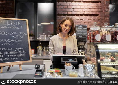 small business, people and service concept - happy woman or barmaid at counter with cashbox working in cafe or coffee shop. happy woman or barmaid with cashbox at cafe. happy woman or barmaid with cashbox at cafe