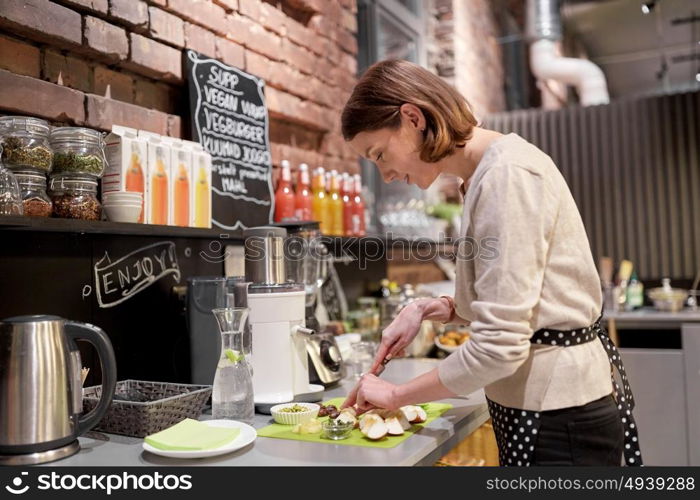 small business, people and service concept - happy woman or barmaid cooking at vegan cafe. happy woman or barmaid cooking at vegan cafe