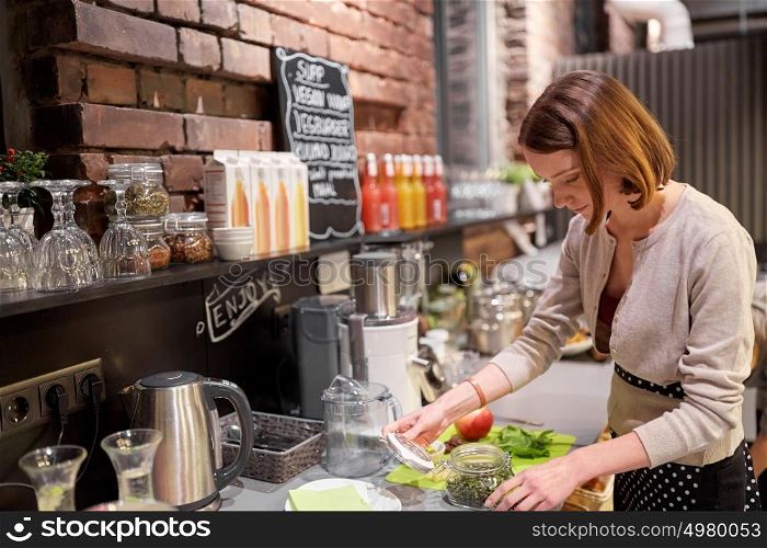 small business, people and service concept - happy woman or barmaid cooking at vegan cafe. happy woman or barmaid cooking at vegan cafe