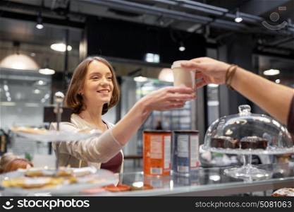 small business, people and service concept - happy woman taking coffee cup from seller at vegan cafe. happy woman taking coffee cup from seller at cafe