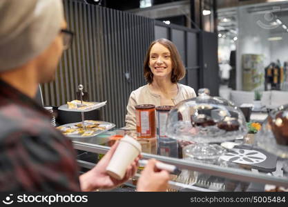 small business, people and service concept - man or barman with coffee cup and marker serving happy female customer at vegan cafe. woman and man or barman with coffee cup at cafe