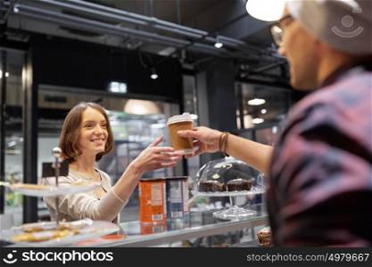 small business, people and service concept - seller giving coffee cup to woman customer at vegan cafe. seller giving coffee cup to woman customer at cafe