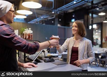 small business, people and service concept - seller giving coffee cup to woman customer at vegan cafe. seller giving coffee cup to woman customer at cafe
