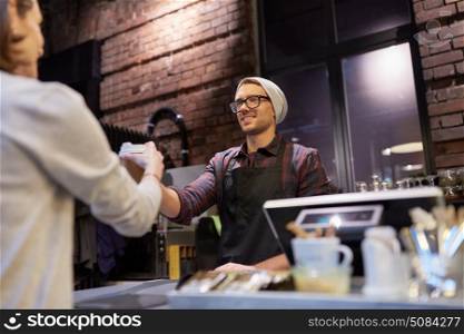 small business, people and service concept - seller giving coffee cup to woman customer at vegan cafe. seller giving coffee cup to woman customer at cafe. seller giving coffee cup to woman customer at cafe