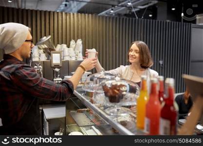 small business, people and service concept - seller giving coffee cup to woman customer at vegan cafe. seller giving coffee cup to woman customer at cafe. seller giving coffee cup to woman customer at cafe