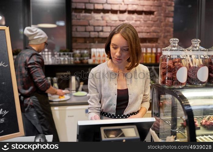 small business, people and service concept - woman or barmaid at counter with cashbox working in cafe or coffee shop. woman or barmaid with cashbox at cafe
