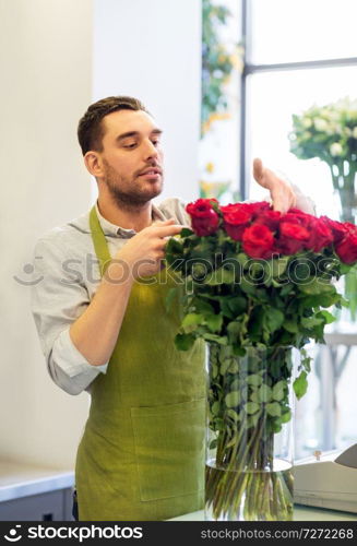 small business, sale and floristry concept - florist or seller setting red roses at flower shop. florist or seller setting red roses at flower shop