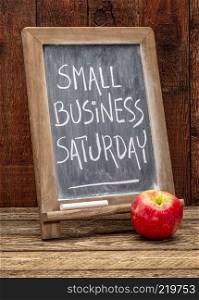 Small Business Saturday sign - white chalk handwriting on a blackboard agains rustic barn wood - holiday shopping concept
