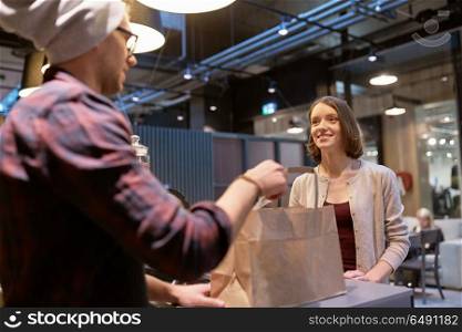 small business, takeaway food, people and service concept - man or seller giving paper bag and money change to happy female customer at vegan cafe. seller giving paper bag and money to woman at cafe. seller giving paper bag and money to woman at cafe