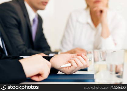 Small business team or working group having a brainstorm meeting in the office, very close-up shots on details, focus on hands in front