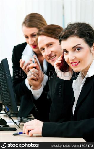 Small business team working in the office on their phones and computers in a shared project