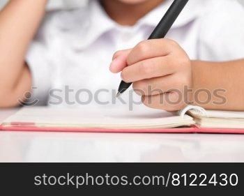 Small businesswoman taking notes while working in the office, close up. Children and business concepts