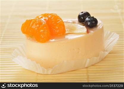 Small cake with white icing and tangerines on bamboo table cloth