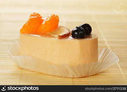 Small cake with white icing and tangerines on bamboo table cloth