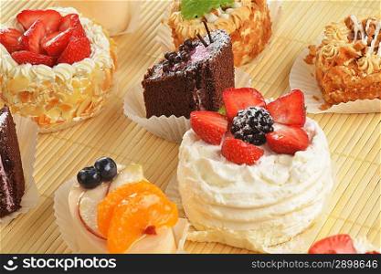 Small cakes with cream and berries on bamboo table cloth