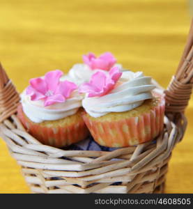 Small cakes with sweet icing in wicker basket