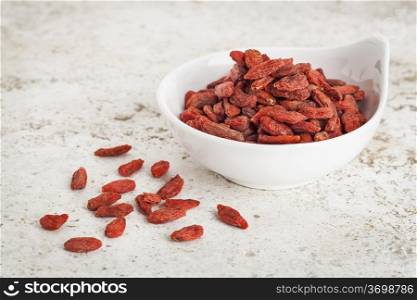 small ceramic bowl of dried goji berries against a ceramic tile background with a copy space