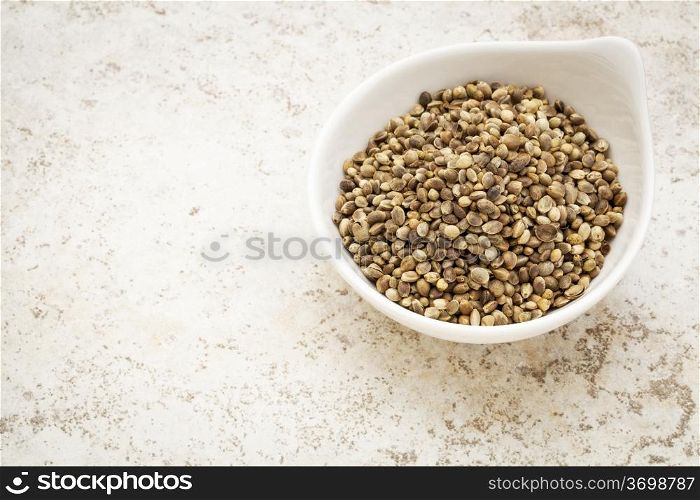 small ceramic bowl of dry hemp seeds against a ceramic tile background with a copy space