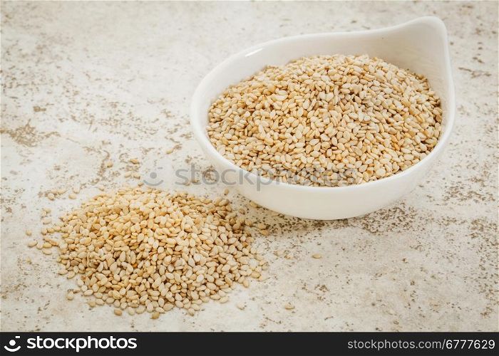 small ceramic bowl of unhulled sesame seeds against a ceramic tile background with a copy space