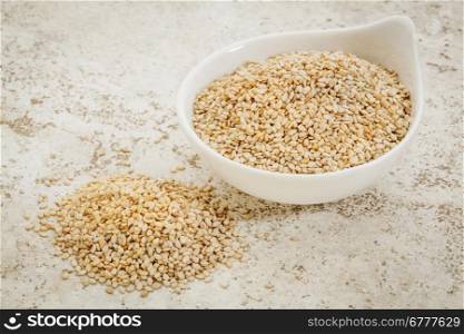 small ceramic bowl of unhulled sesame seeds against a ceramic tile background with a copy space