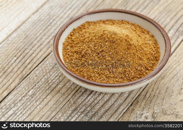 small ceramic bowl of unrefined coconut palm sugar against a white painted grunge wood background