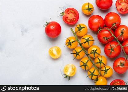 Small cherry tomatoes assortment, fresh red ripe on branch, red and yellow, whole and cut in half, on rustic table flat lay with copy space.