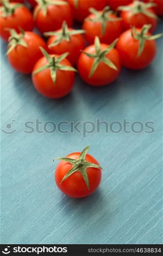 Small cherry tomatoes with leaf on a blue wooden surface