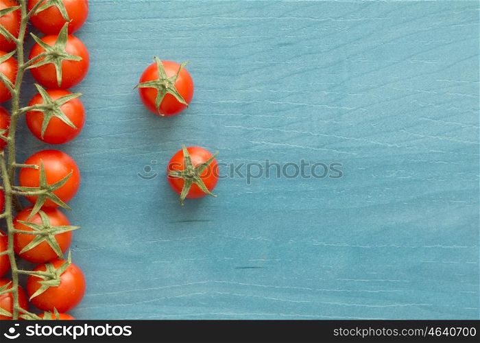 Small cherry tomatoes with leaf on a blue wooden surface