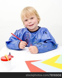 Small child coloring on a large sheet of paper and smiling at the camera