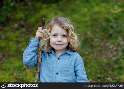 Small child enjoying of a sunny day. Small child with long blond hair with a stick enjoying of a sunny day