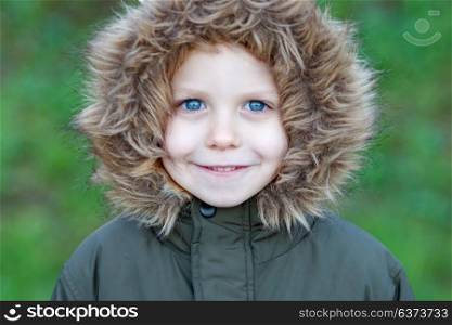 Small child in the park with a warm coat and a green grass of background