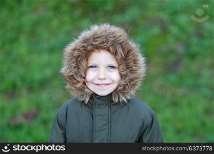 Small child in the park with a warm coat and a green grass of background