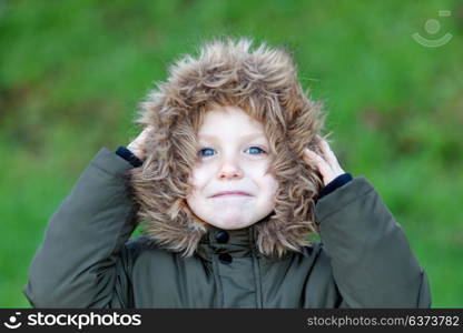 Small child in the park with a warm coat and a green grass of background