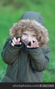 Small child in the park with a warm coat and a green grass of background